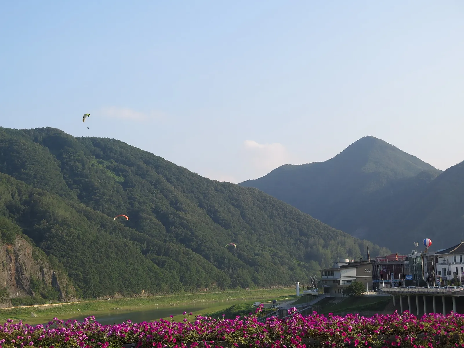 Paragliders circling above green hills and the Namhangang valley in Danyang