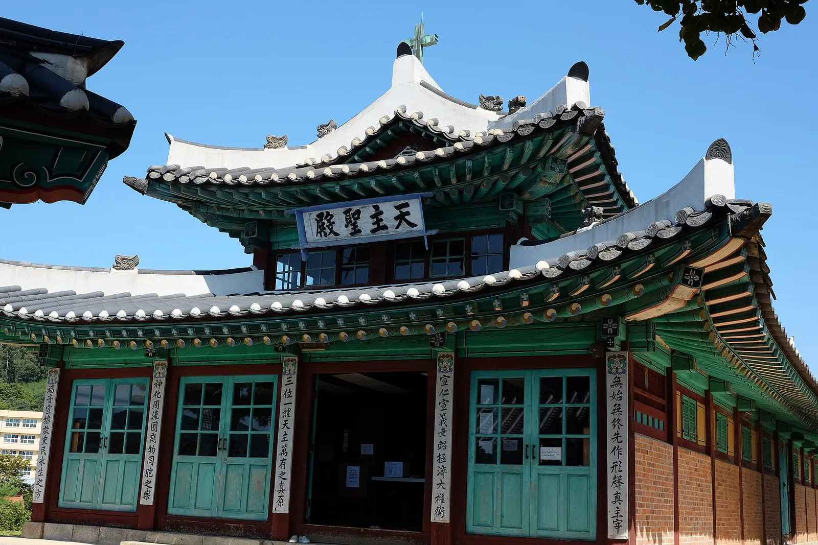 Ganghwa Anglican Church, a hanok-style church with green-painted doors and a tiled roof under a blue sky