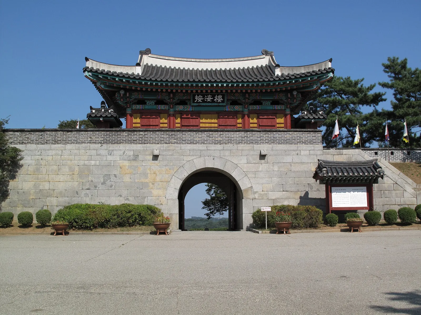 Stone gate with a painted wooden pavilion on top at Gwangseongbo fortress under a clear blue sky