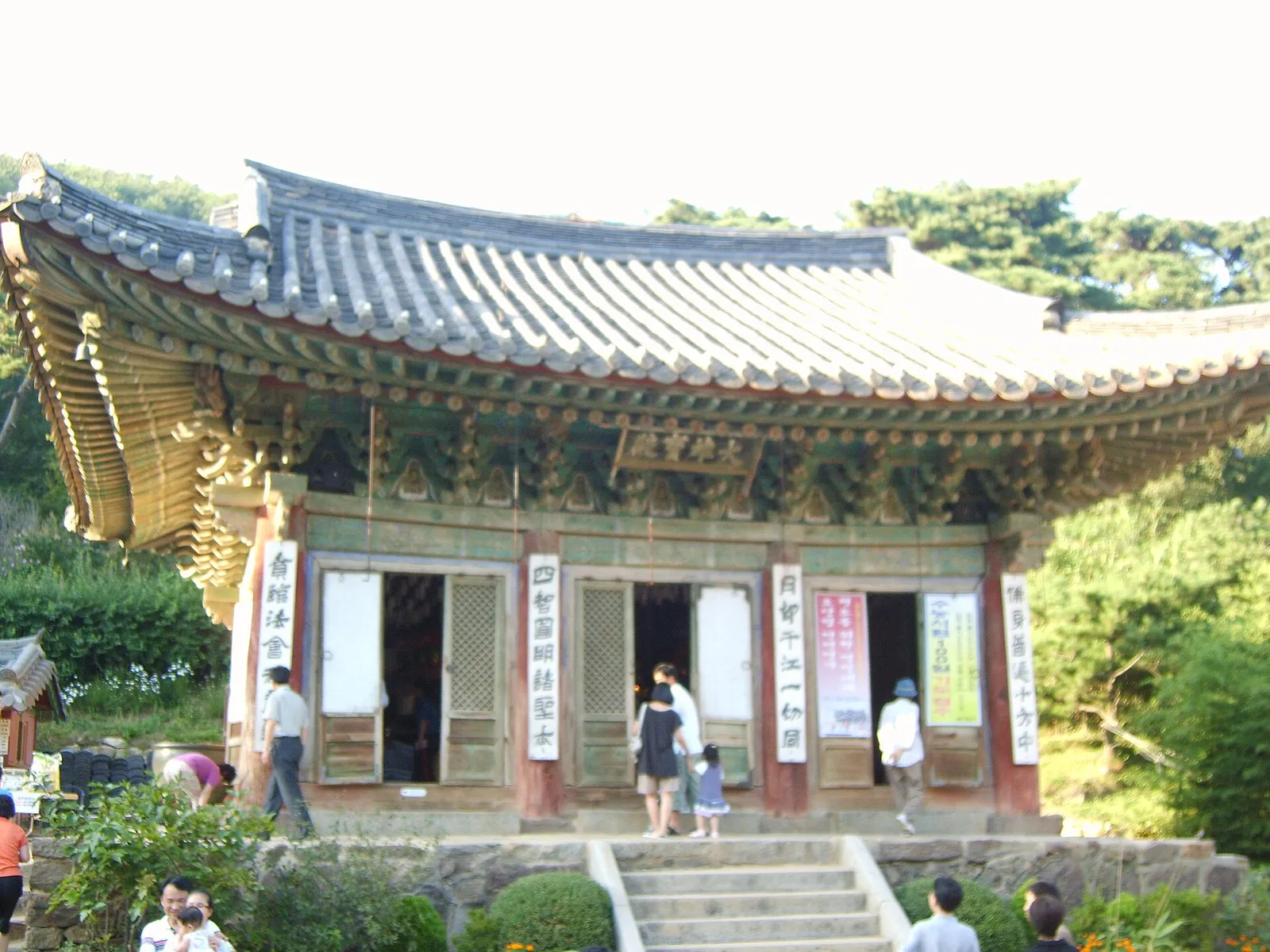 Daeungjeon, the main hall of Jeondeungsa, with a curved tiled roof, carved eaves and visitors on the steps