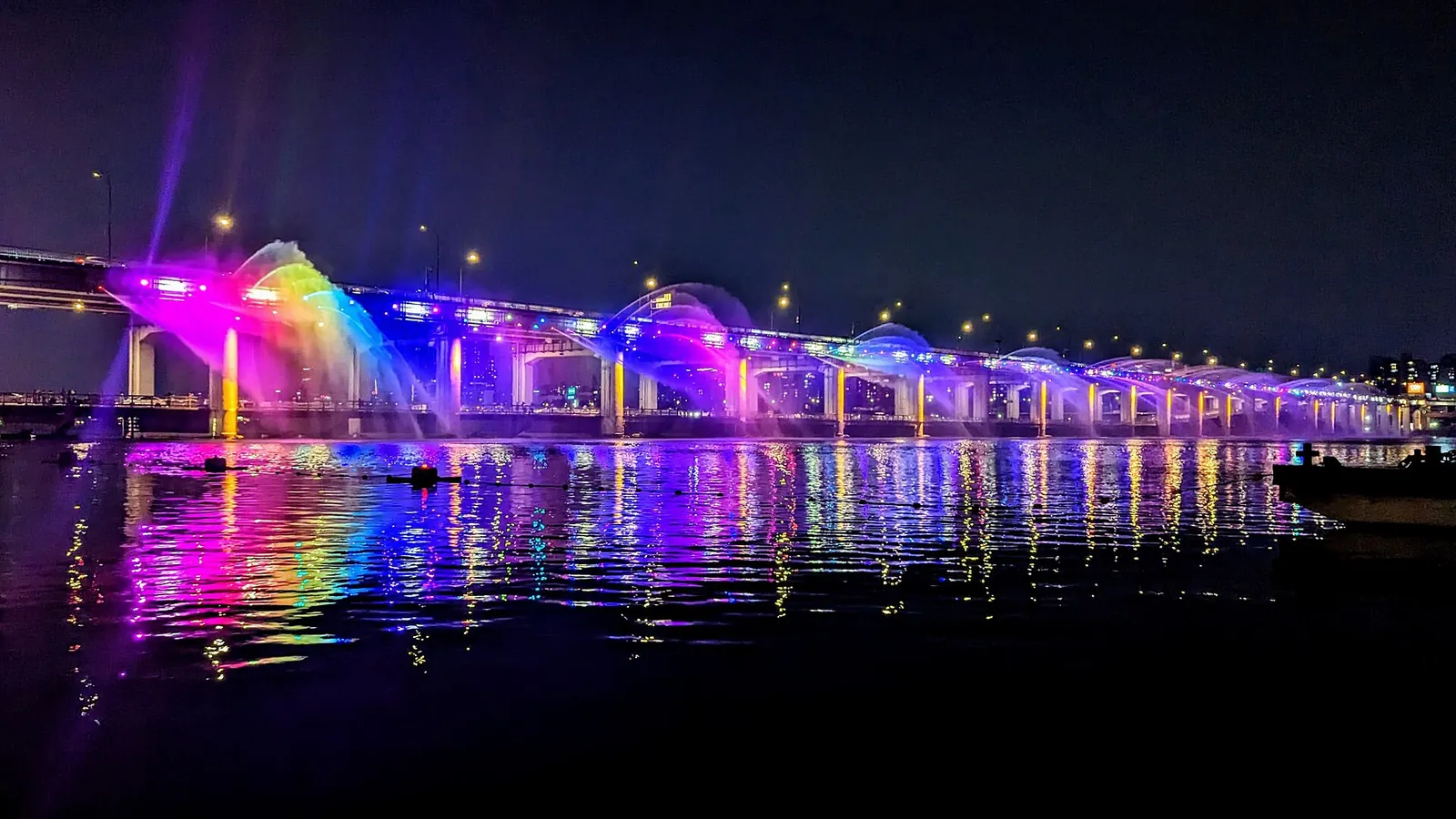 Banpo Bridge lit at night with jets of the Moonlight Rainbow Fountain in purple, pink and blue