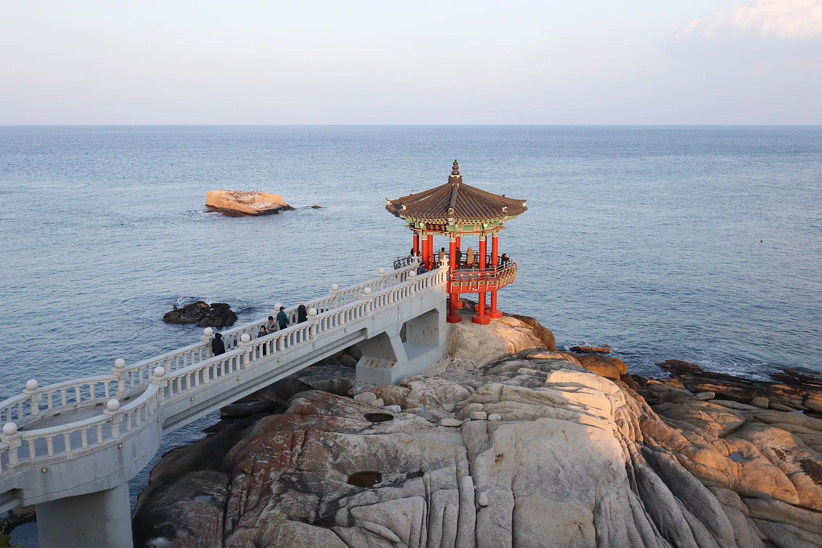 Yeonggeumjeong pavilion at the end of a white bridge over the rocks on the Sokcho shore, with the sea beyond