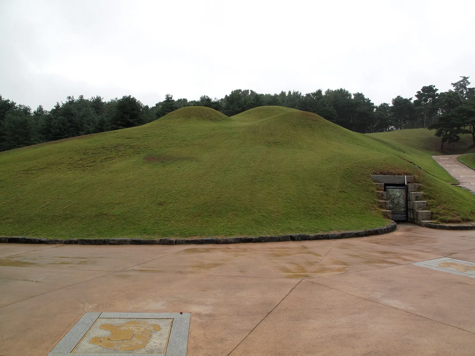 Grass-covered burial mounds of the royal tombs in Gongju with a stone entrance at the base of one mound