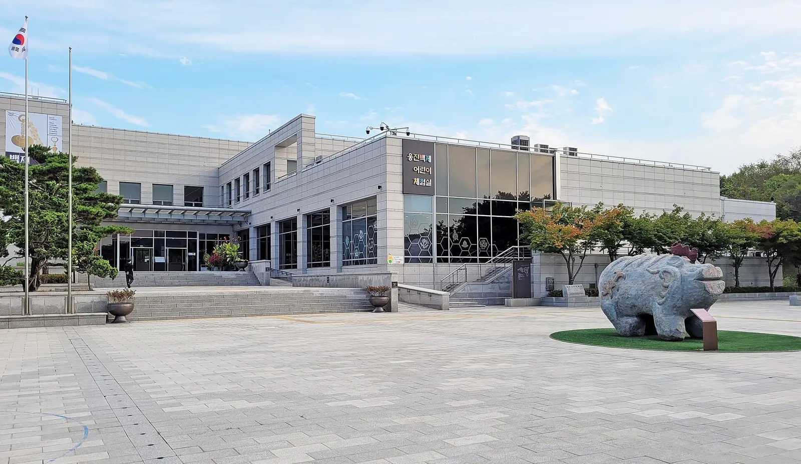 Gongju National Museum building behind a paved forecourt with a large stone tomb-guardian sculpture