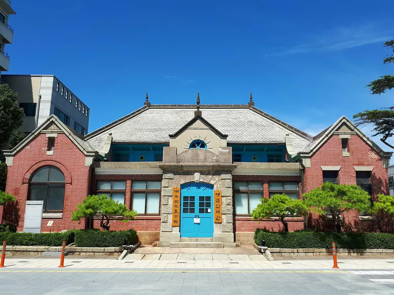 Red-brick Former Gunsan Customs building with a blue central door under a clear blue sky