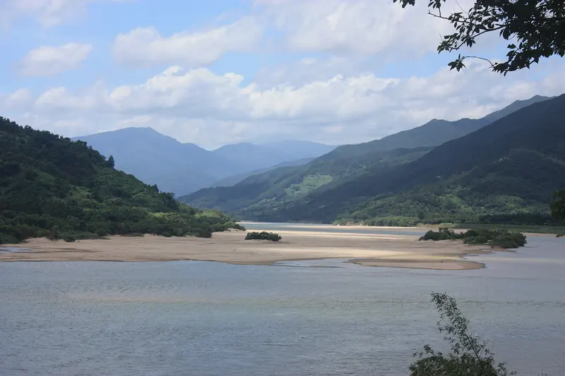 The wide Seomjin River with sandbanks between forested hills north of Hadong town