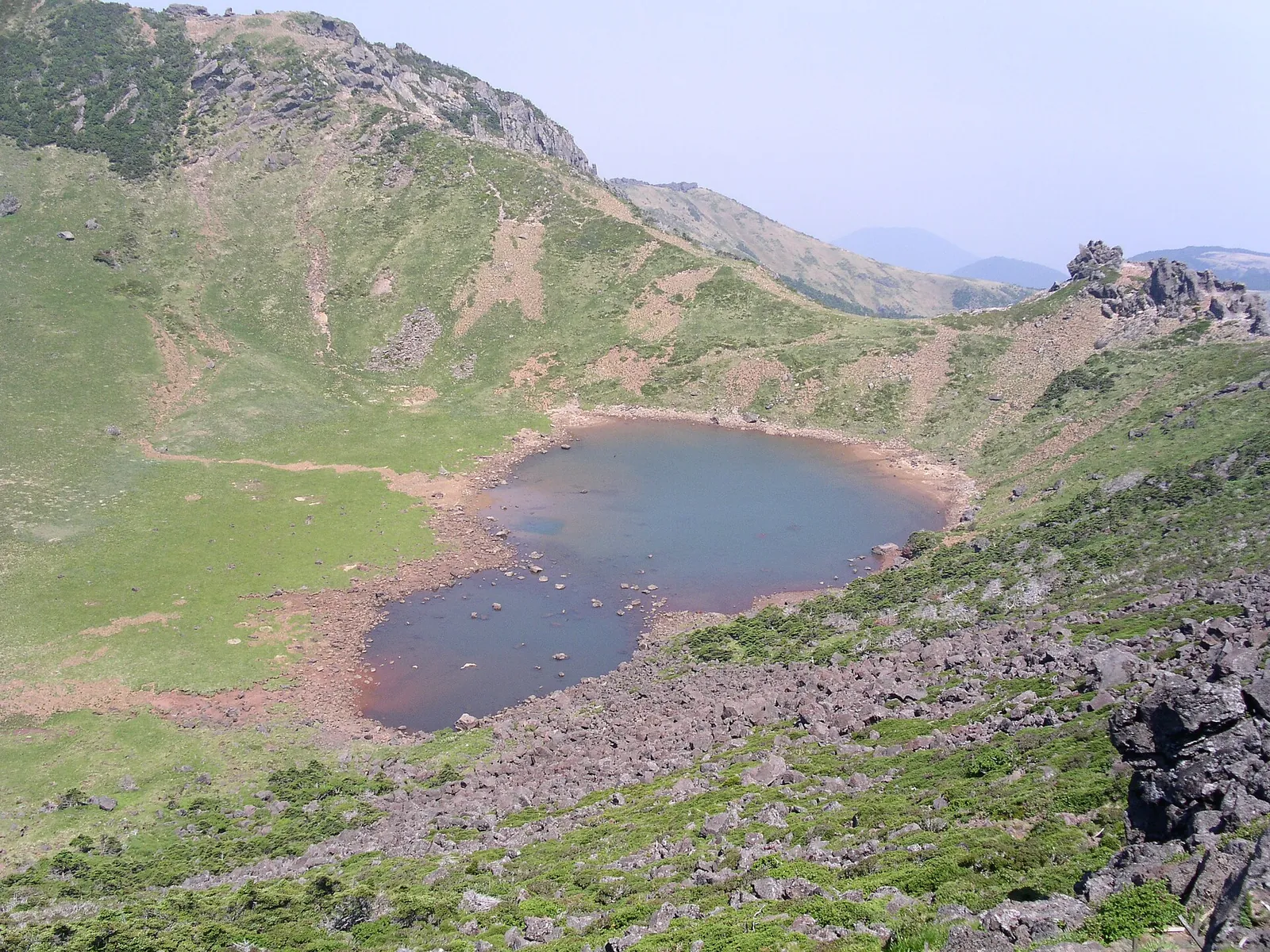 Baengnokdam crater lake inside the green summit crater of Hallasan under a clear sky