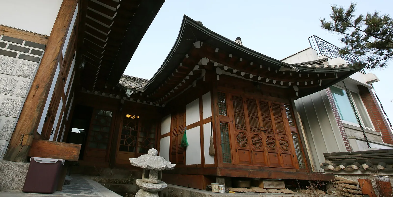 Wooden hanok with lattice doors, a tiled roof and a stone lantern in front in Bukchon, Seoul
