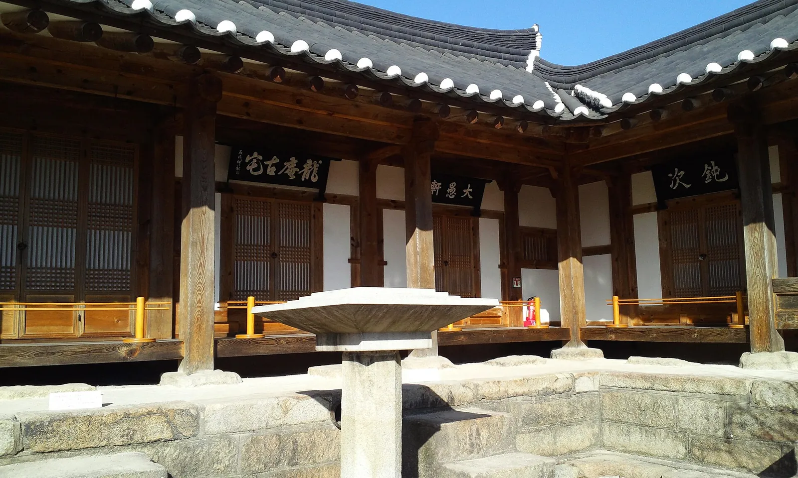 Courtyard of a traditional hanok with wooden pillars, lattice doors and a tiled roof in Gyochon Village, Gyeongju