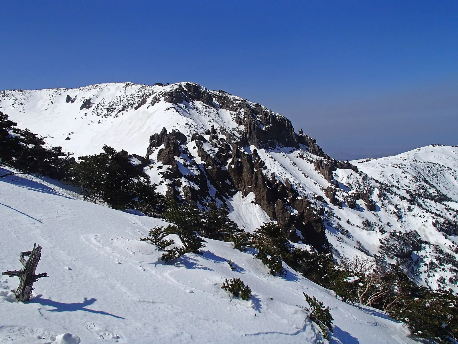 Snow-covered slopes and rocky ridges of Hallasan on Jeju under a deep blue sky
