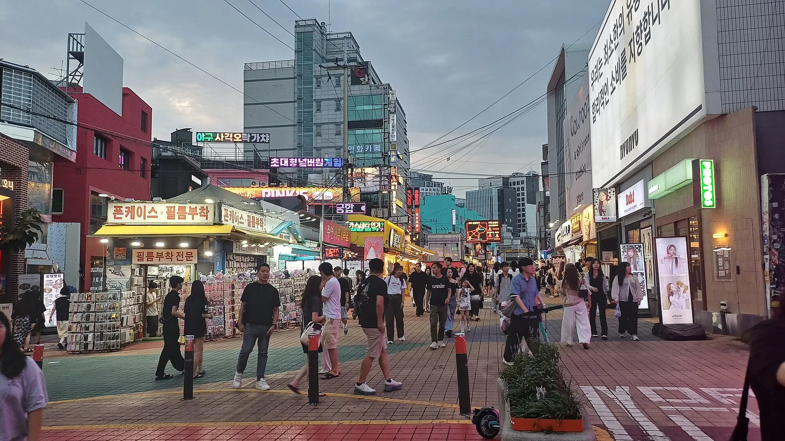 A wide pedestrian street with red paving and shopfronts in Hongdae, Mapo-gu, Seoul