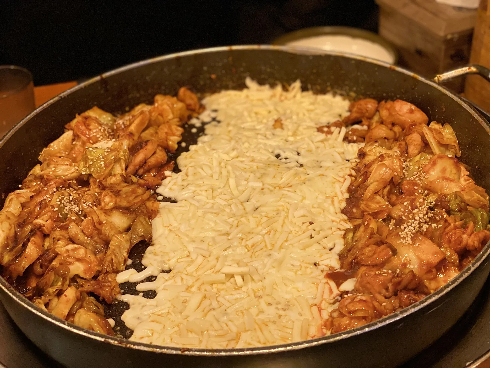 Cheese dakgalbi: spicy stir-fried chicken and cabbage in a griddle pan with a strip of shredded cheese down the middle