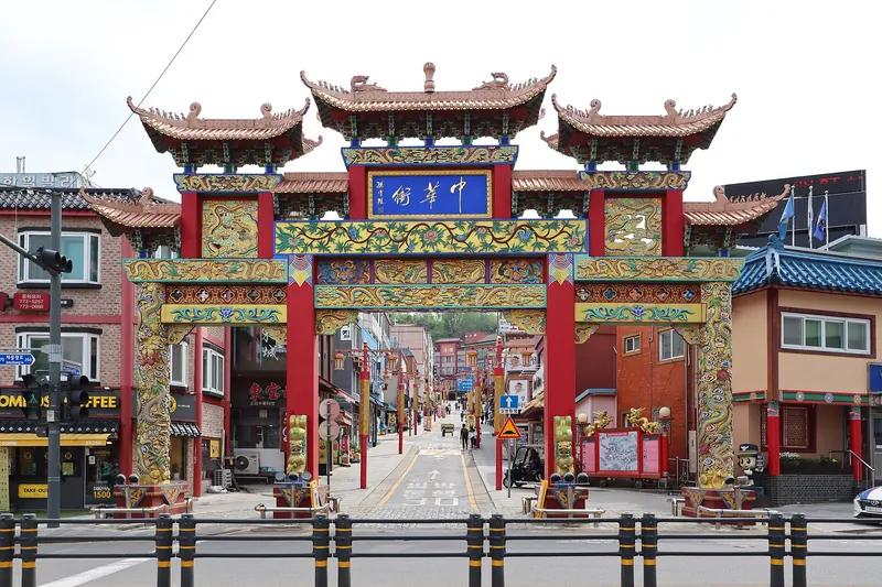 Ornate red and gold paifang gate at the entrance to Incheon Chinatown, with the street beyond