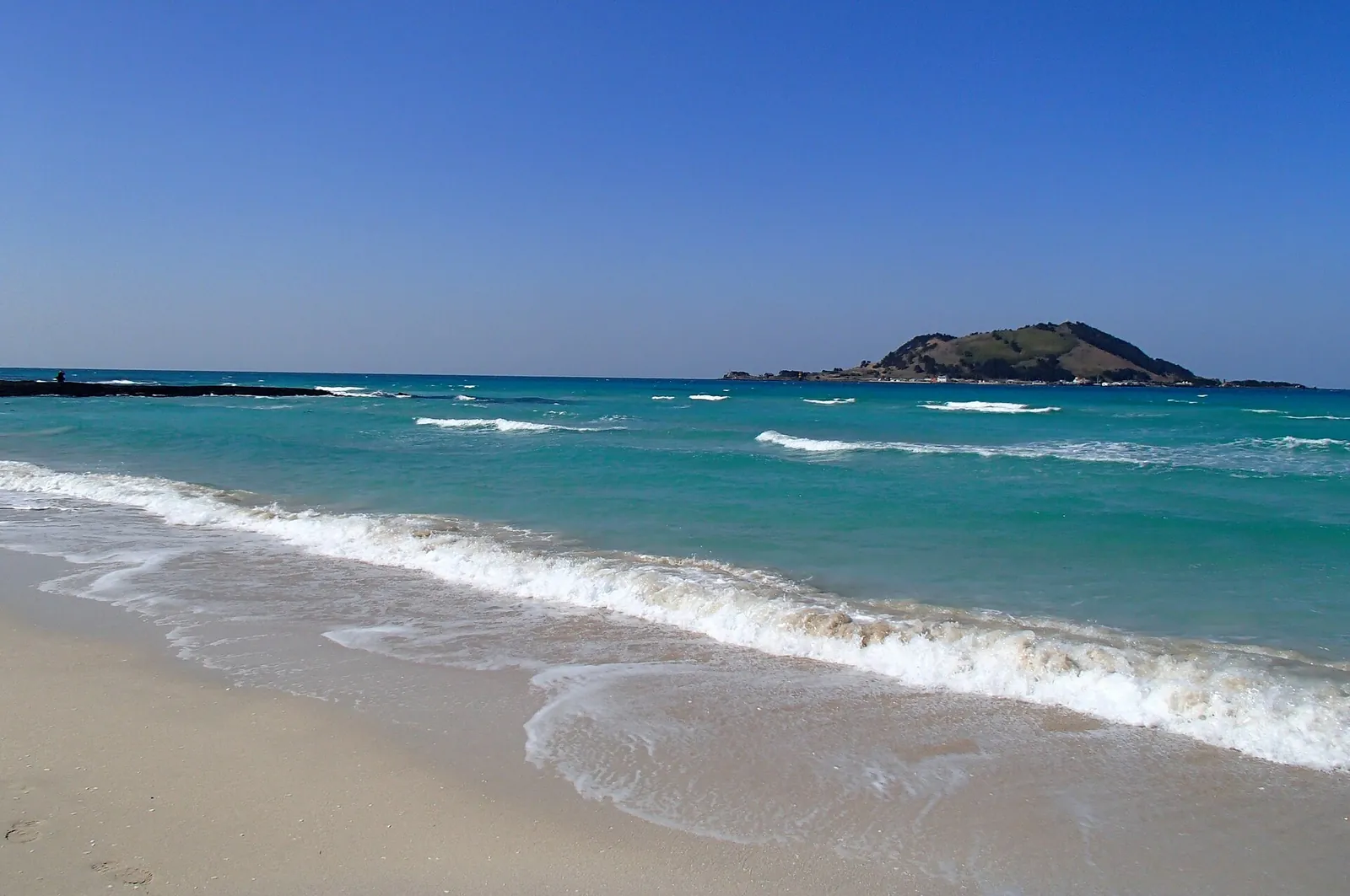 Turquoise water and white sand at Hyeopjae Beach with Biyangdo Island on the horizon