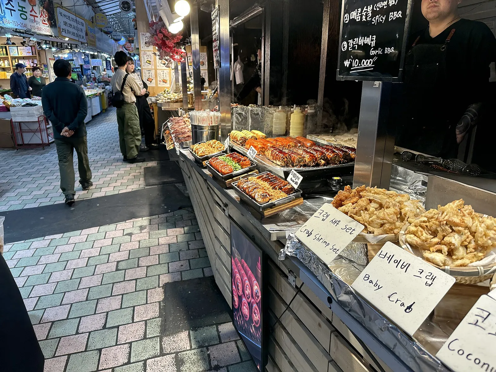Trays of fried snacks and seafood on a stall counter inside Jeju Dongmun Traditional Market