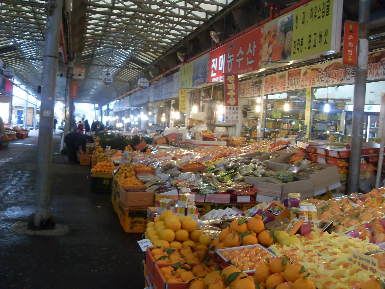 Covered aisle of Dongmun Market lined with stalls of mandarins and other fruit