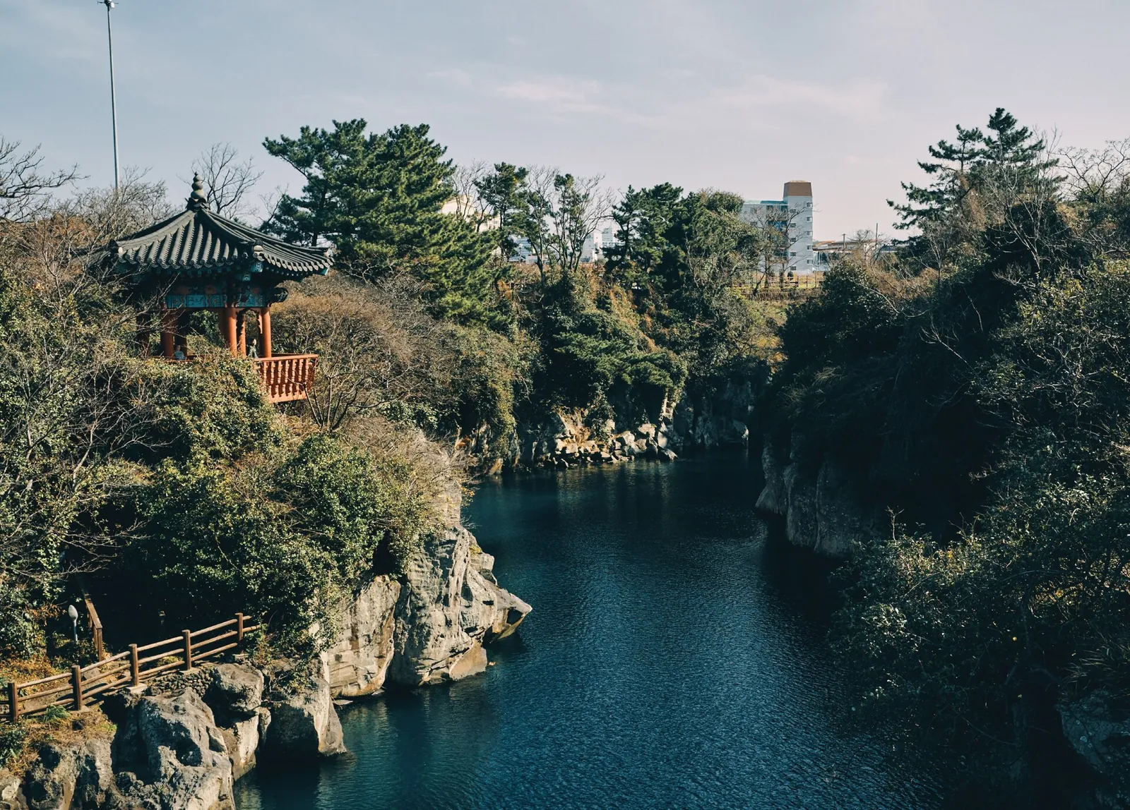 Yongyeon Pond's dark green water in a narrow gorge, with a small pavilion and pines on the cliff top