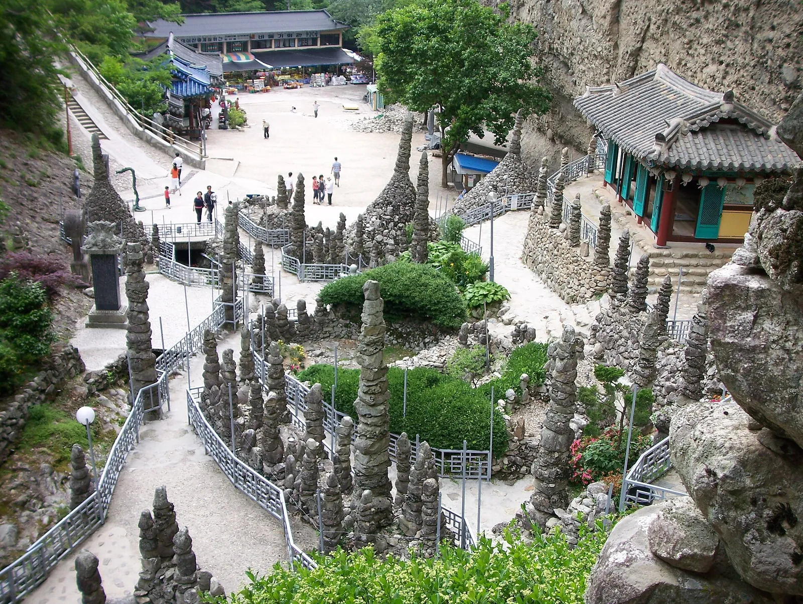Dozens of conical and column-shaped stone towers lining the paths of Tapsa below a rock cliff