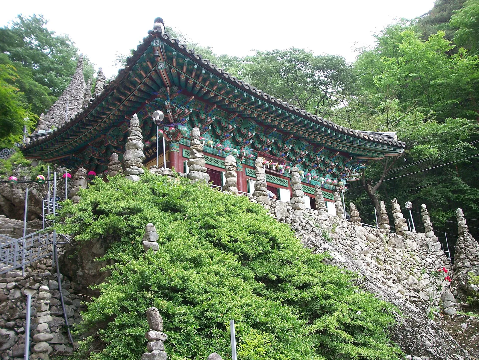 A temple hall with curved roof above a terrace of stacked stone towers at Tapsa