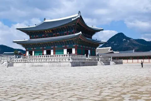 Geunjeongjeon, tronhallen i Gyeongbokgung, under en blå himmel med bjerge bagved
