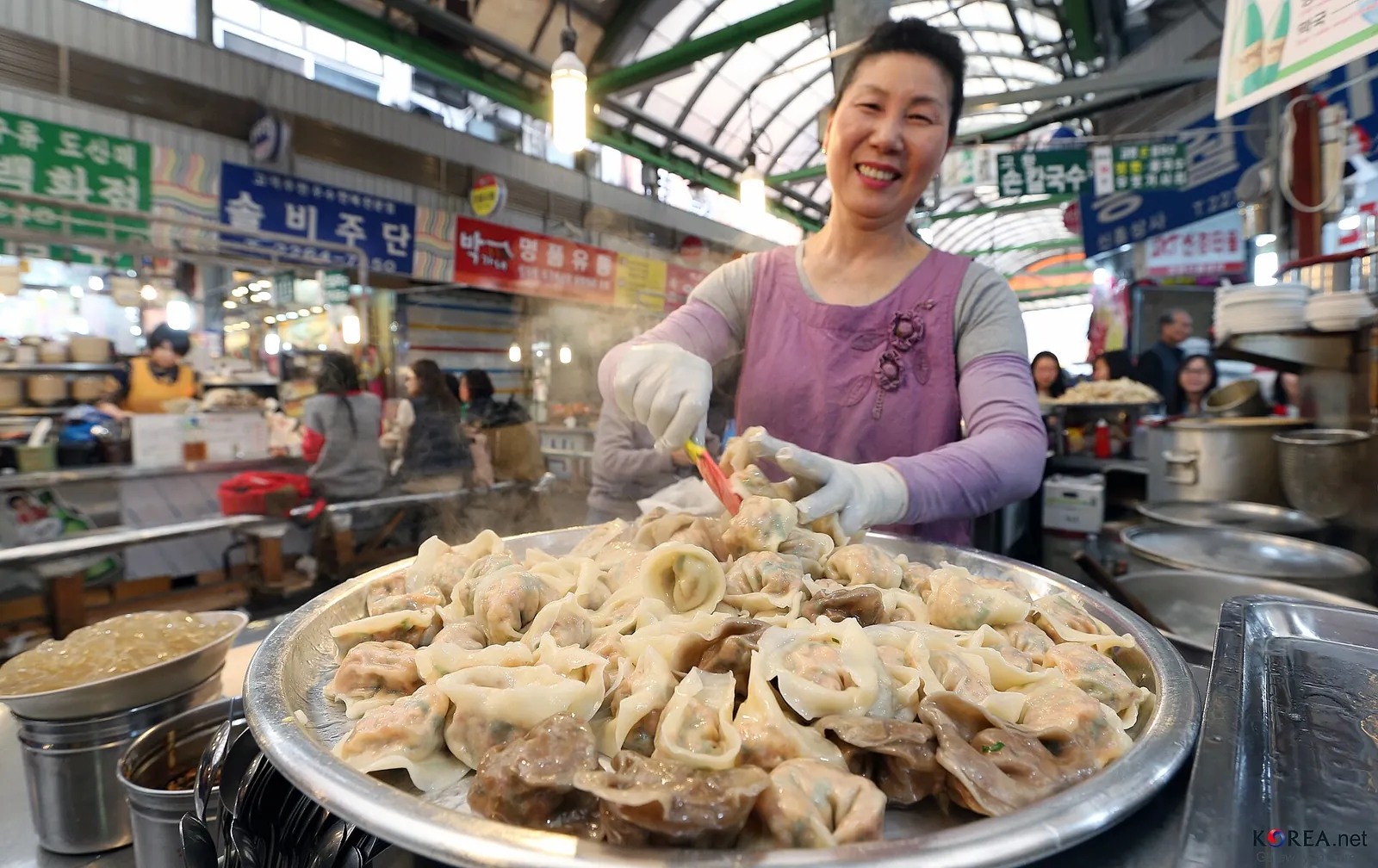 A vendor at Gwangjang Market in Seoul arranging a large tray of freshly made mandu dumplings