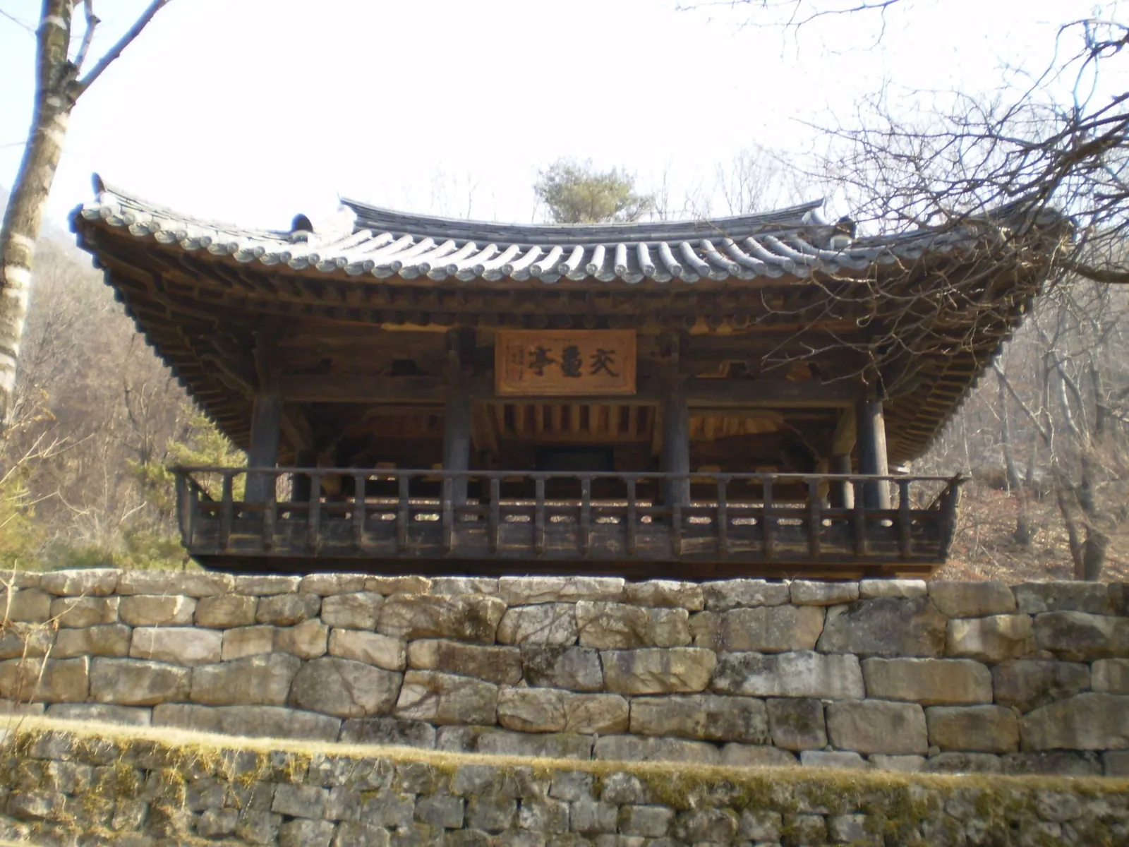 Gyogwijeong, a wooden pavilion with a tiled roof on a stone terrace beside the Mungyeong Saejae trail