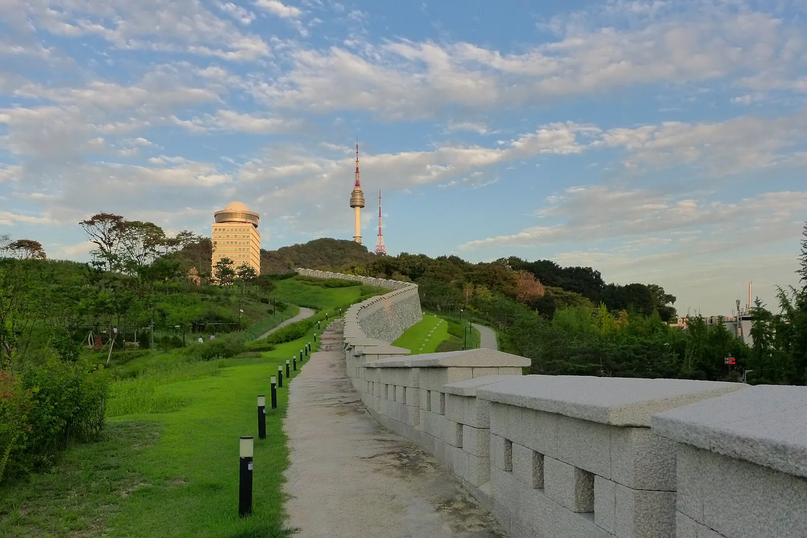 N Seoul Tower rising above the trees beside a stretch of the old Seoul city wall in Namsan Park