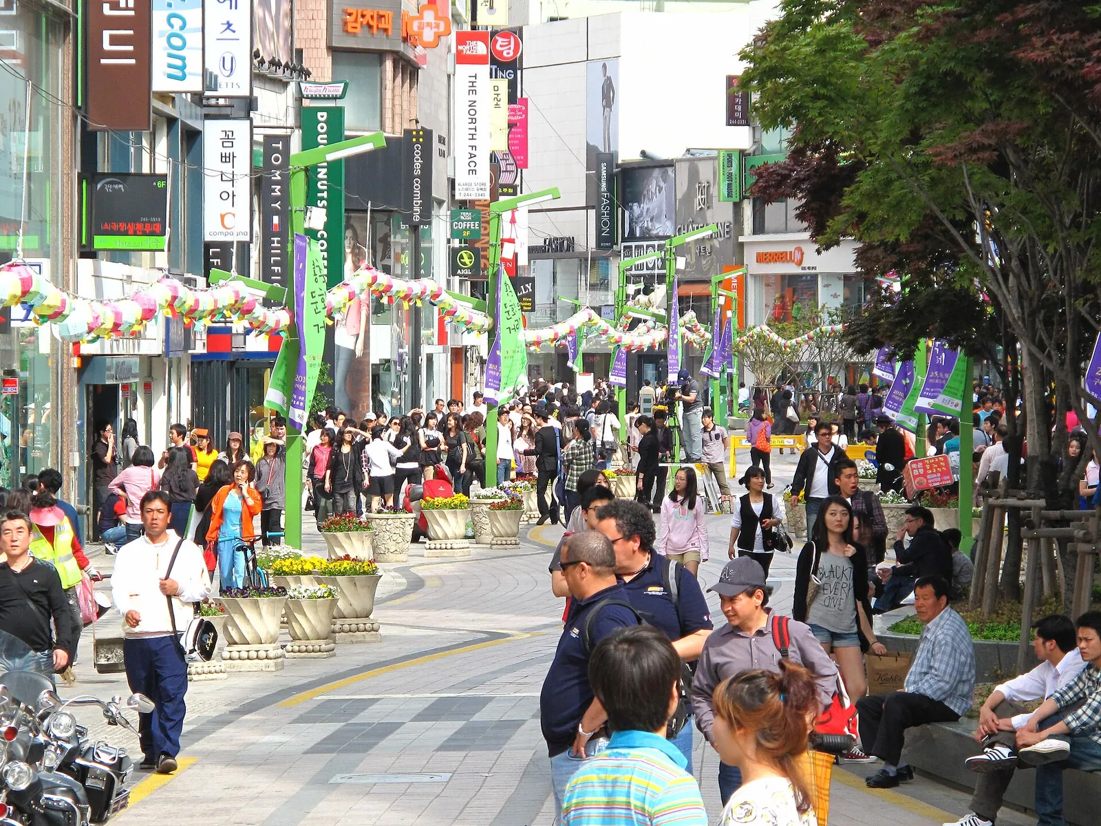 Crowds walking along a pedestrian shopping street in Nampo-dong lined with shops and banners