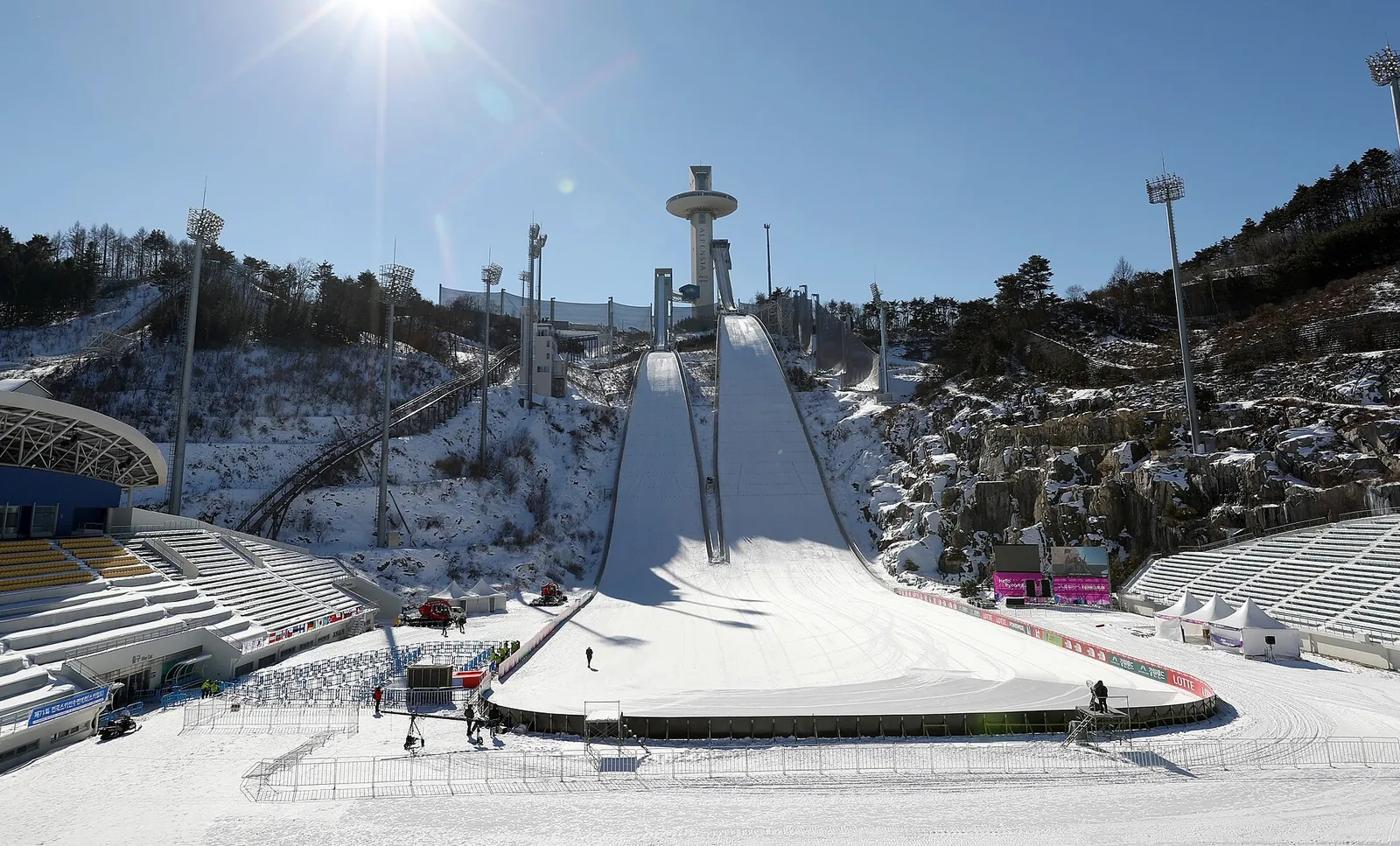 Snow-covered landing slope and tower of the Alpensia ski jumping stadium under a clear blue sky