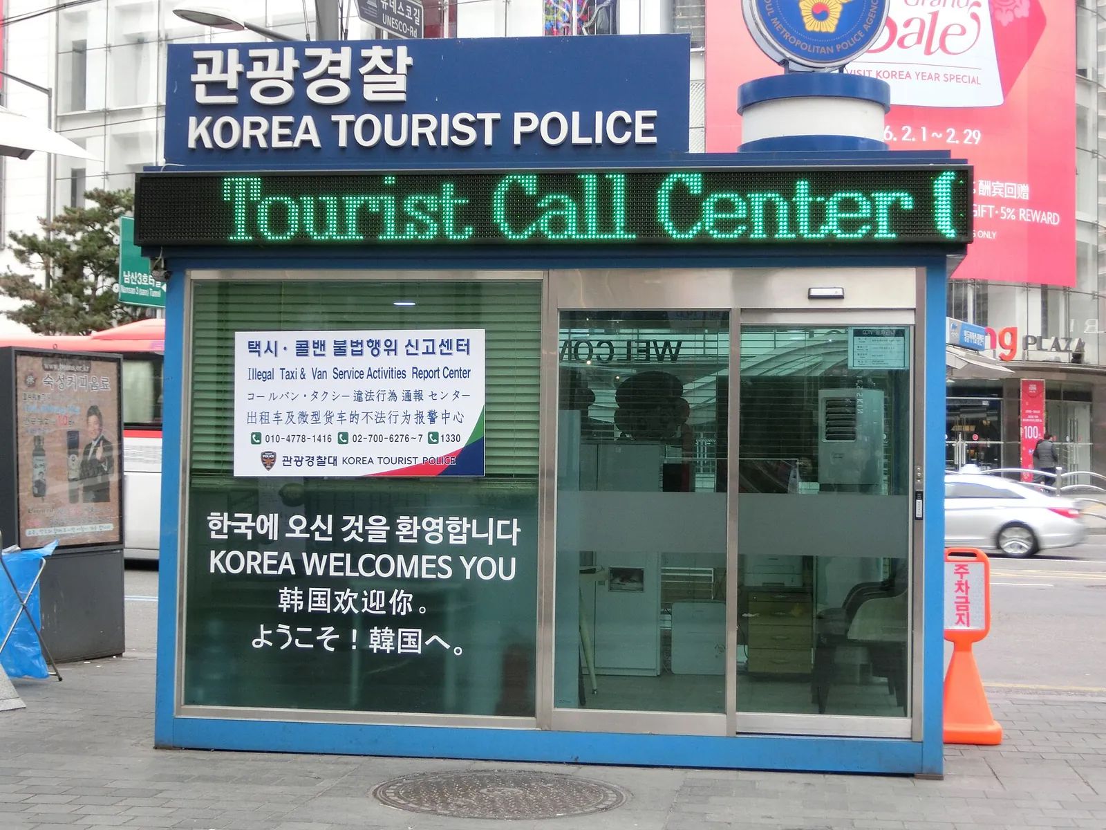 Korea Tourist Police booth with a Tourist Call Center sign and multilingual welcome notice on a Myeongdong street