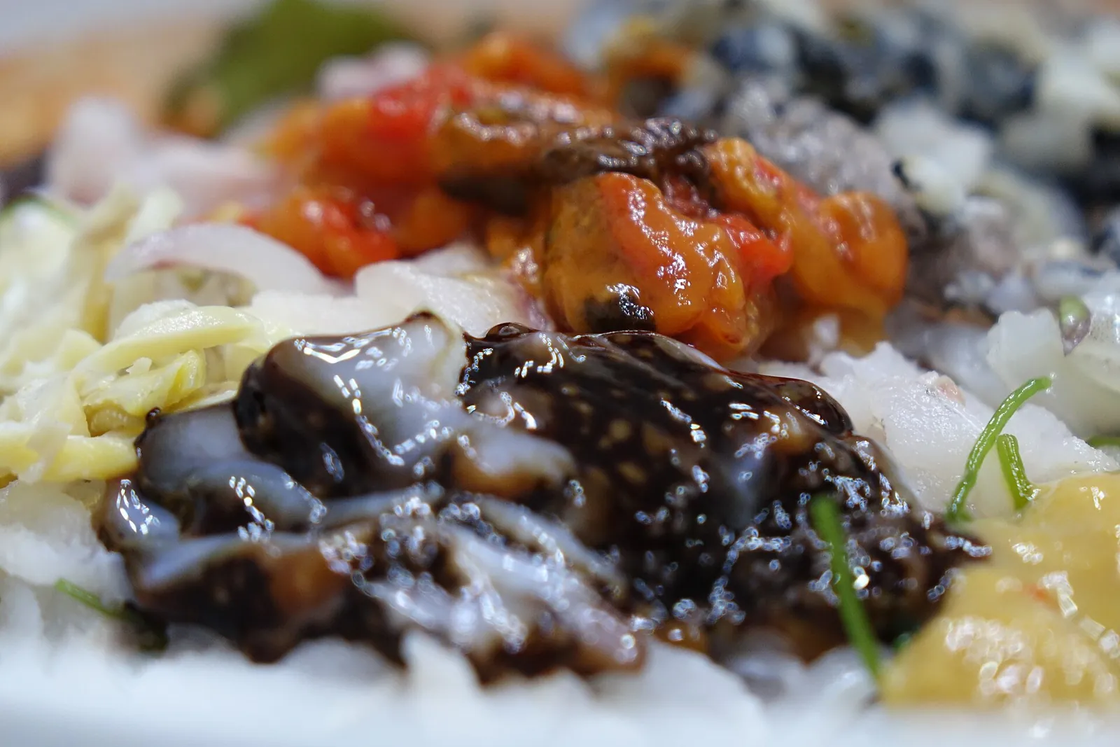 Close-up of mulhoe: sliced raw seafood and shredded vegetables in a red, spicy dressing