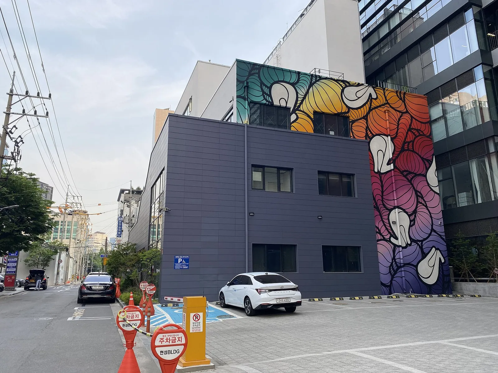 A large colourful mural painted on the side of a building on a Seongsu-dong street