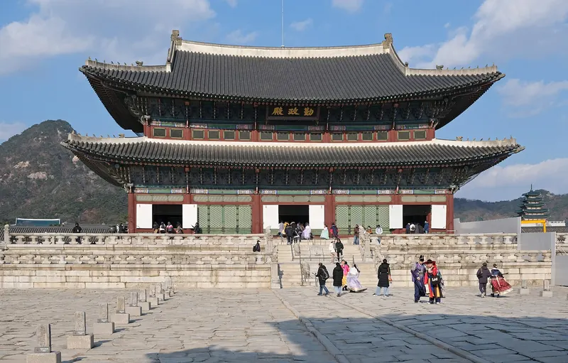 Geunjeongjeon, the throne hall of Gyeongbokgung Palace, on its stone terrace under a blue sky with Bugaksan behind