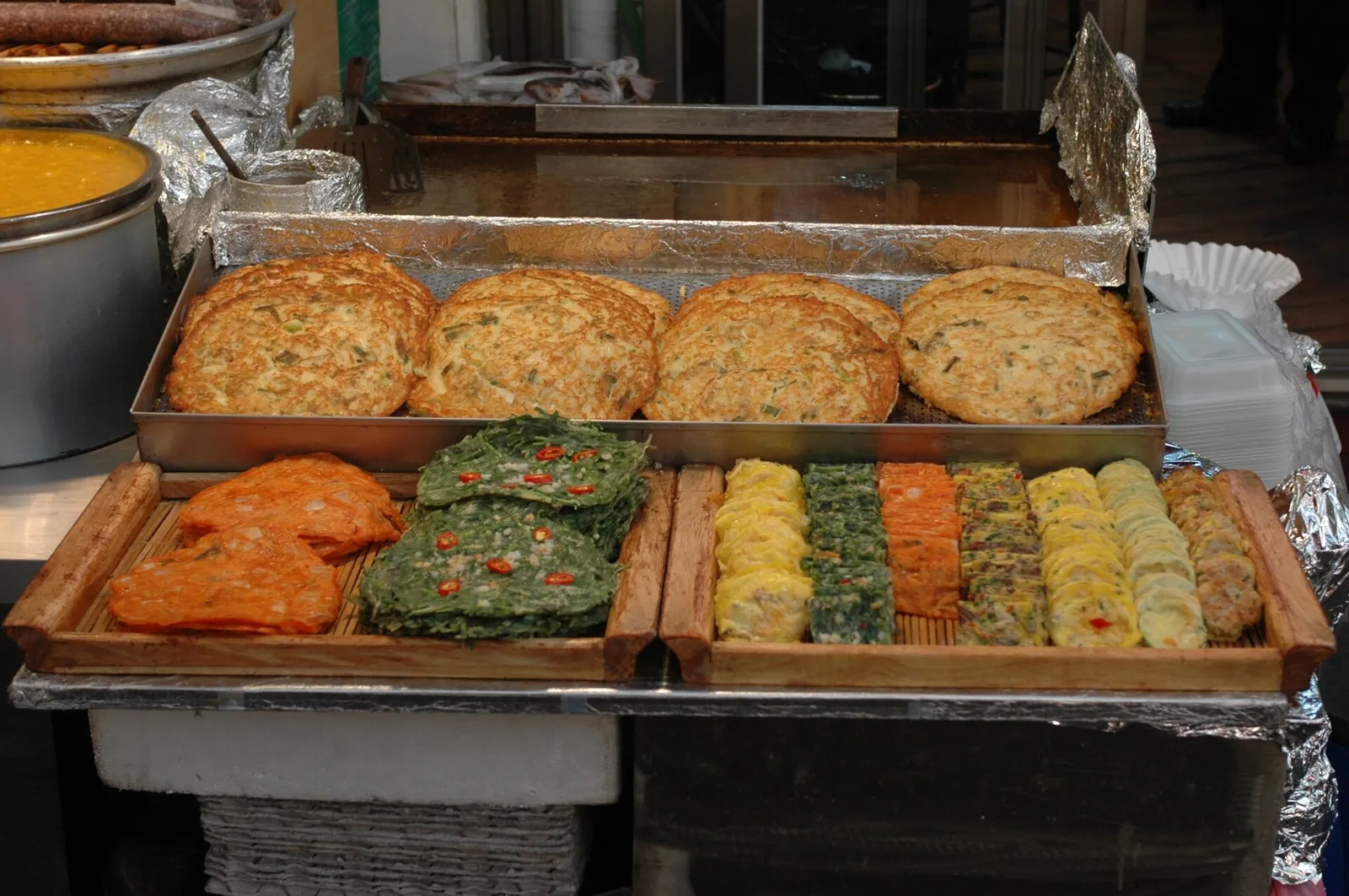 Trays of bindaetteok mung bean pancakes and other pan-fried jeon on display at a Gwangjang Market stall