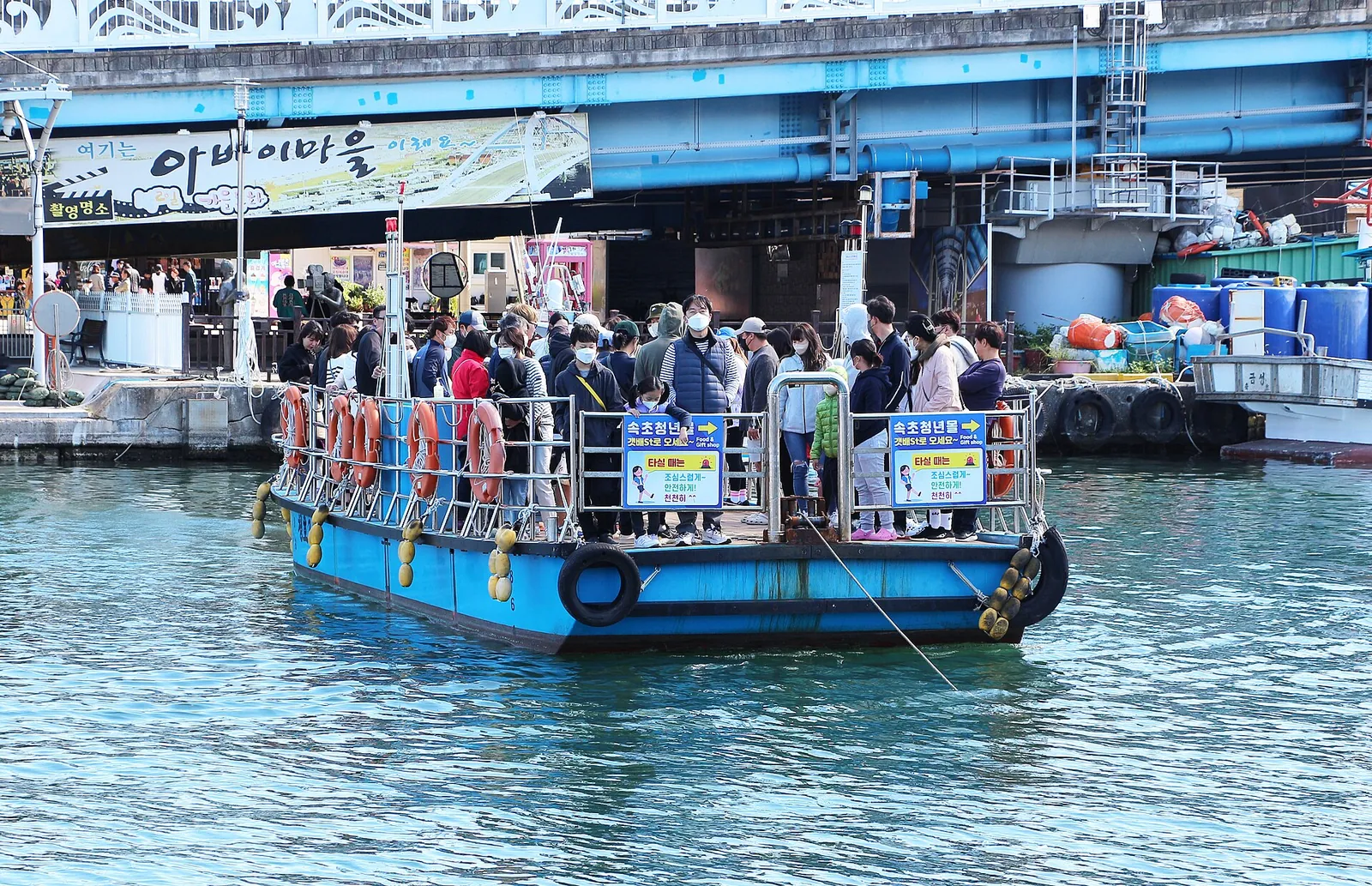 Passengers on the flat gaetbae barge crossing the channel to Abai Village under the Seorak Geumgang Bridge