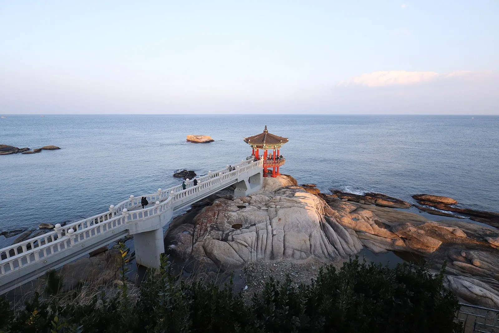 Yeonggeumjeong pavilion on a rocky outcrop reached by a white bridge over the East Sea at dusk