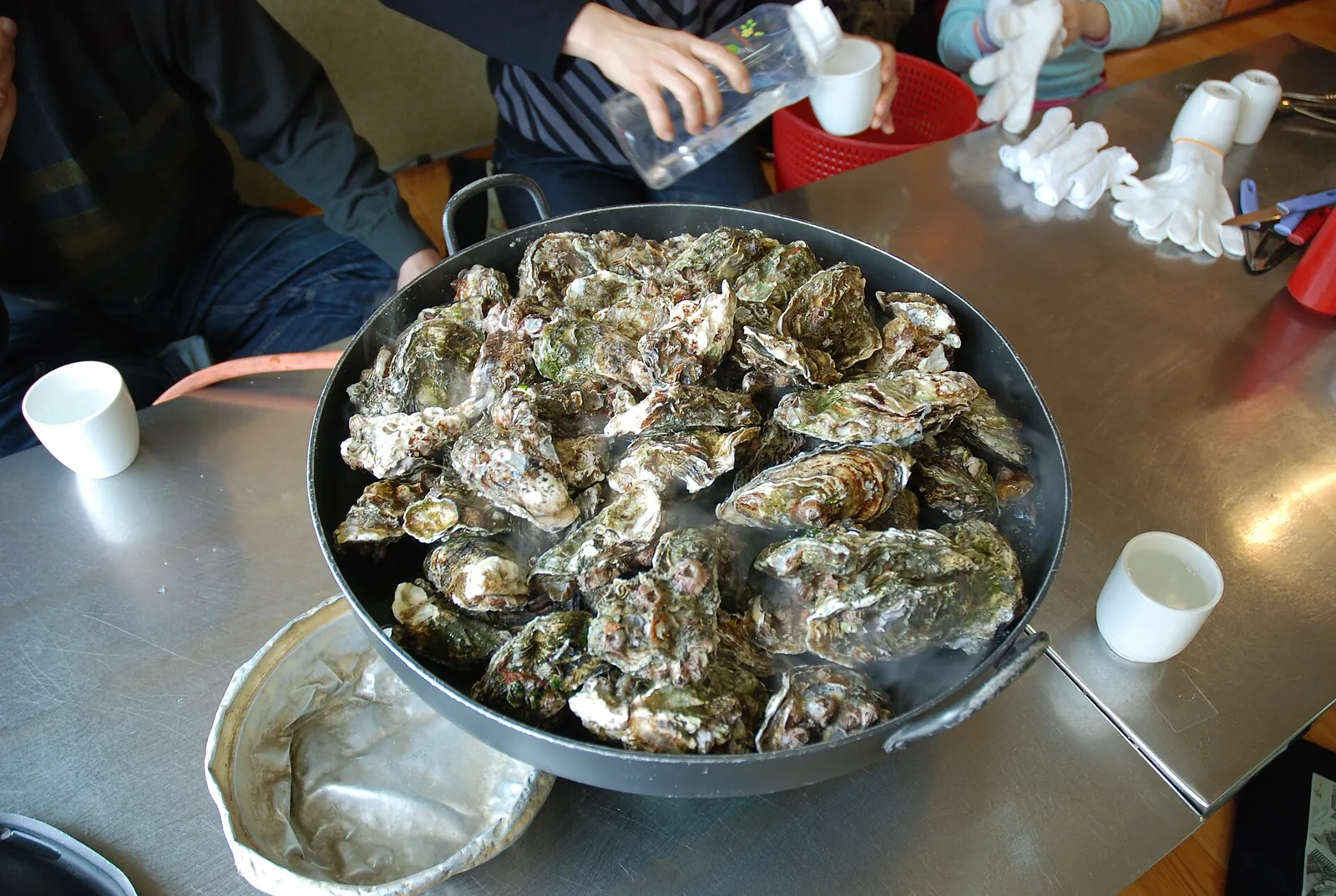 A large pan of steamed oysters in their shells on a restaurant table on Geoje
