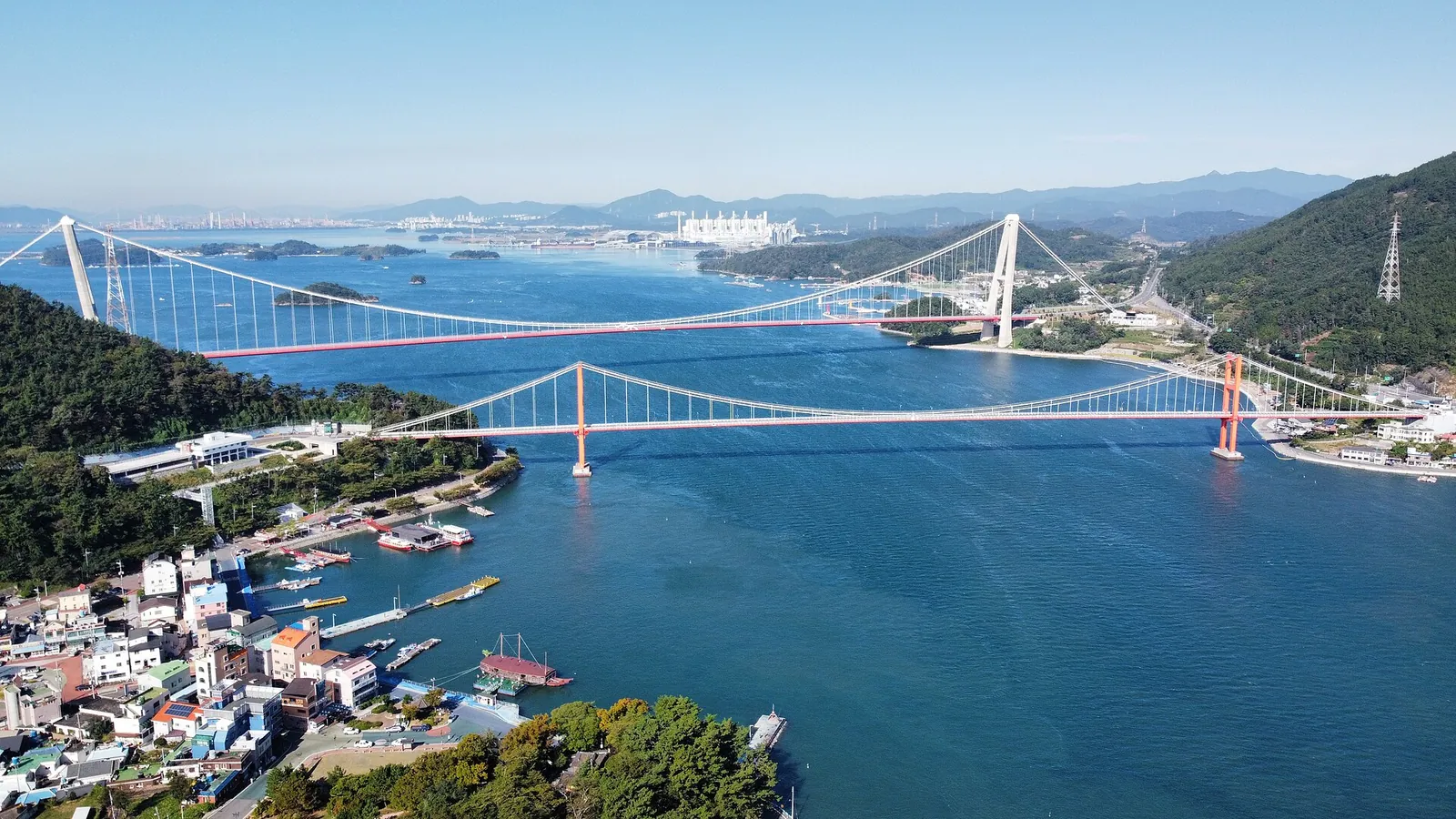 Aerial view of the red Namhae Bridge and the white Noryang Bridge crossing the blue Noryang strait between Hadong and Namhae