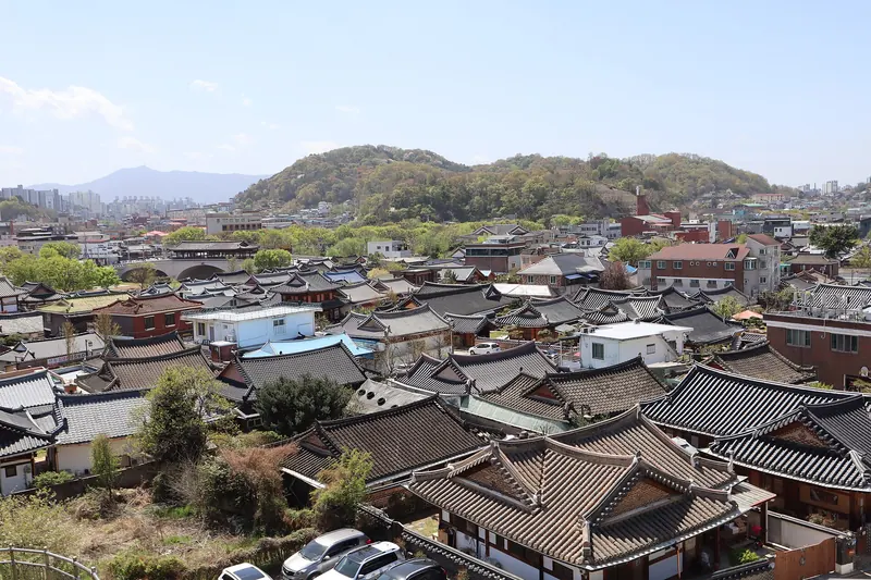 Tiled hanok roofs of Jeonju Hanok Village spreading towards wooded hills under a clear sky