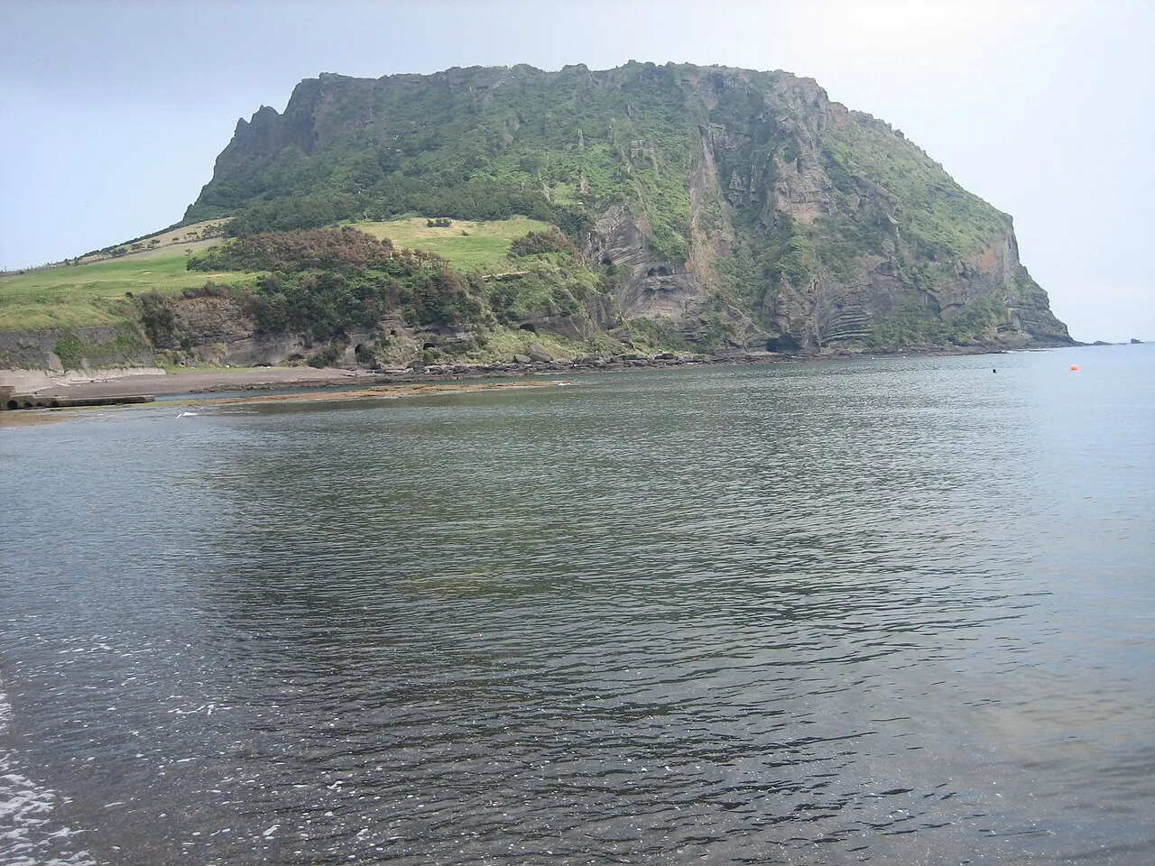 Seongsan Ilchulbong tuff cone above calm water on the east coast of Jeju