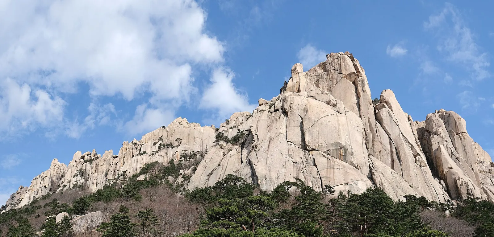 Takkede granittinder på Ulsanbawi under en blå himmel med hvide skyer i Seoraksan Nationalpark