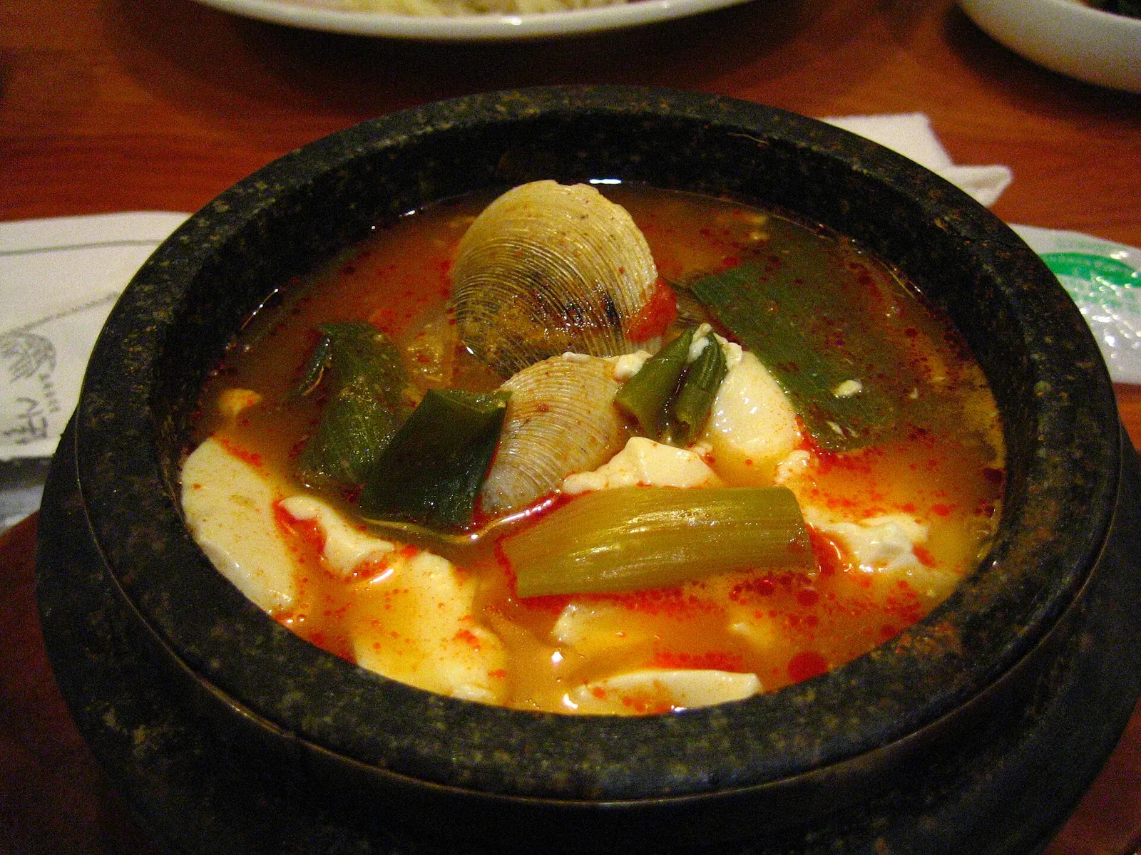 Sundubu-jjigae, en stærk stuvning med blød tofu, grøntsager og skaldyr i en sort stengryde