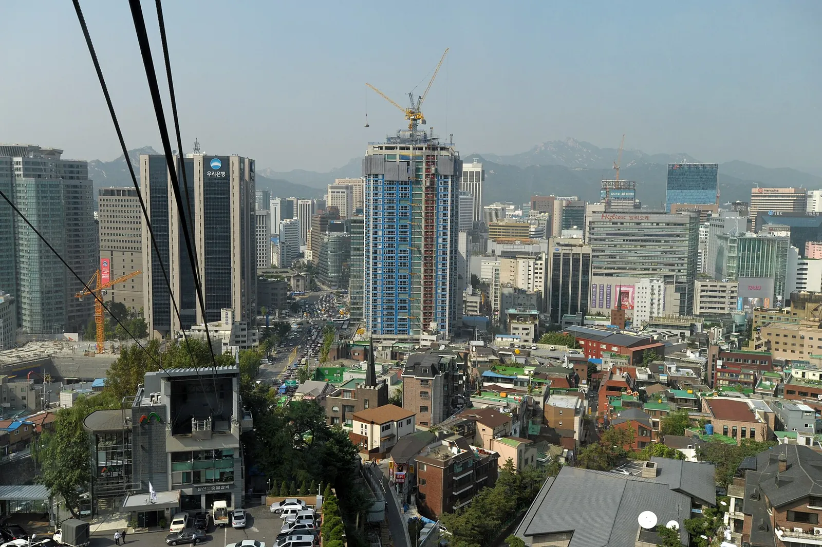 Tage og kontortårne i Myeongdong-kvarteret set fra en kabelbane på Namsan, med bjerge i baggrunden