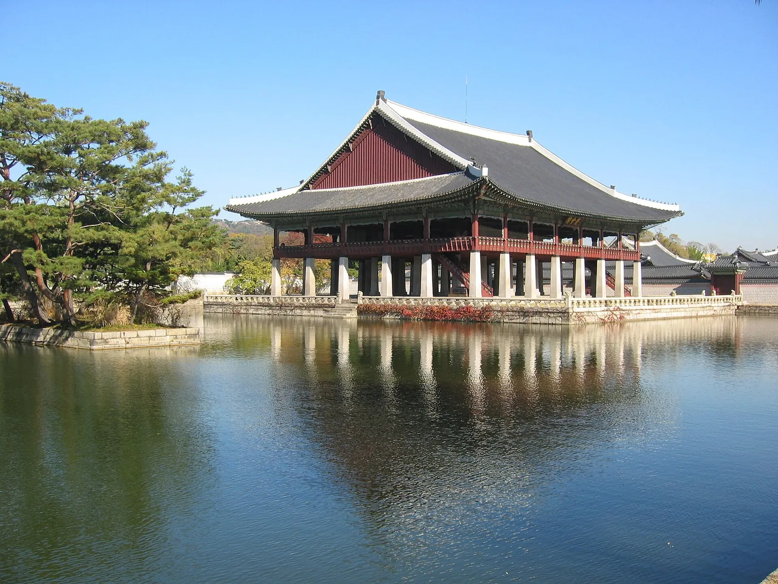 Pavillonen Gyeonghoeru ved Gyeongbokgung-paladset, en hævet hal på stensøjler med et mørkt tegltag, spejlet i en dam under en blå himmel
