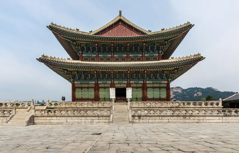 Geunjeongjeon, the two-tiered throne hall of Gyeongbokgung Palace, on its stone terrace under a blue sky