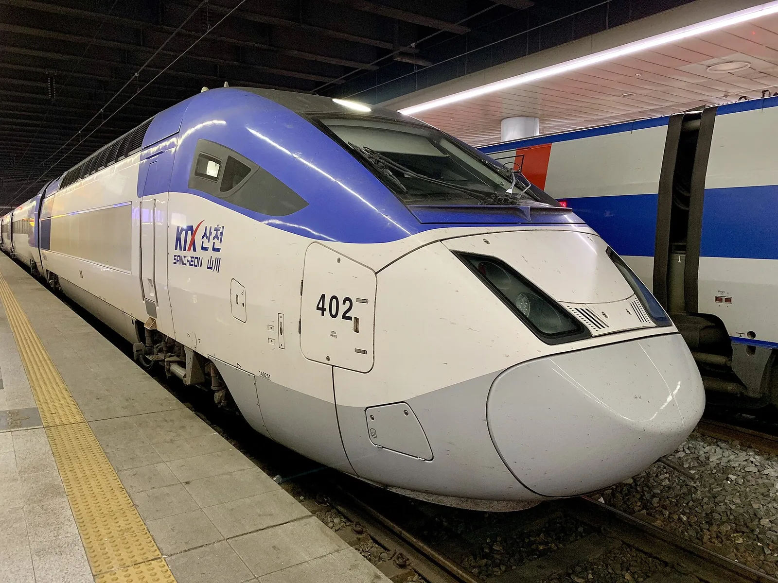A white and blue KTX high-speed train waiting at a platform in Seoul Station