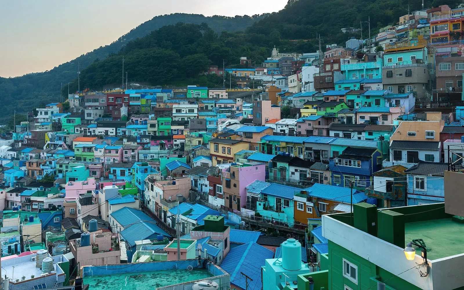 Tiers of brightly painted houses climbing a hillside in Gamcheon Culture Village, Busan, at sunset