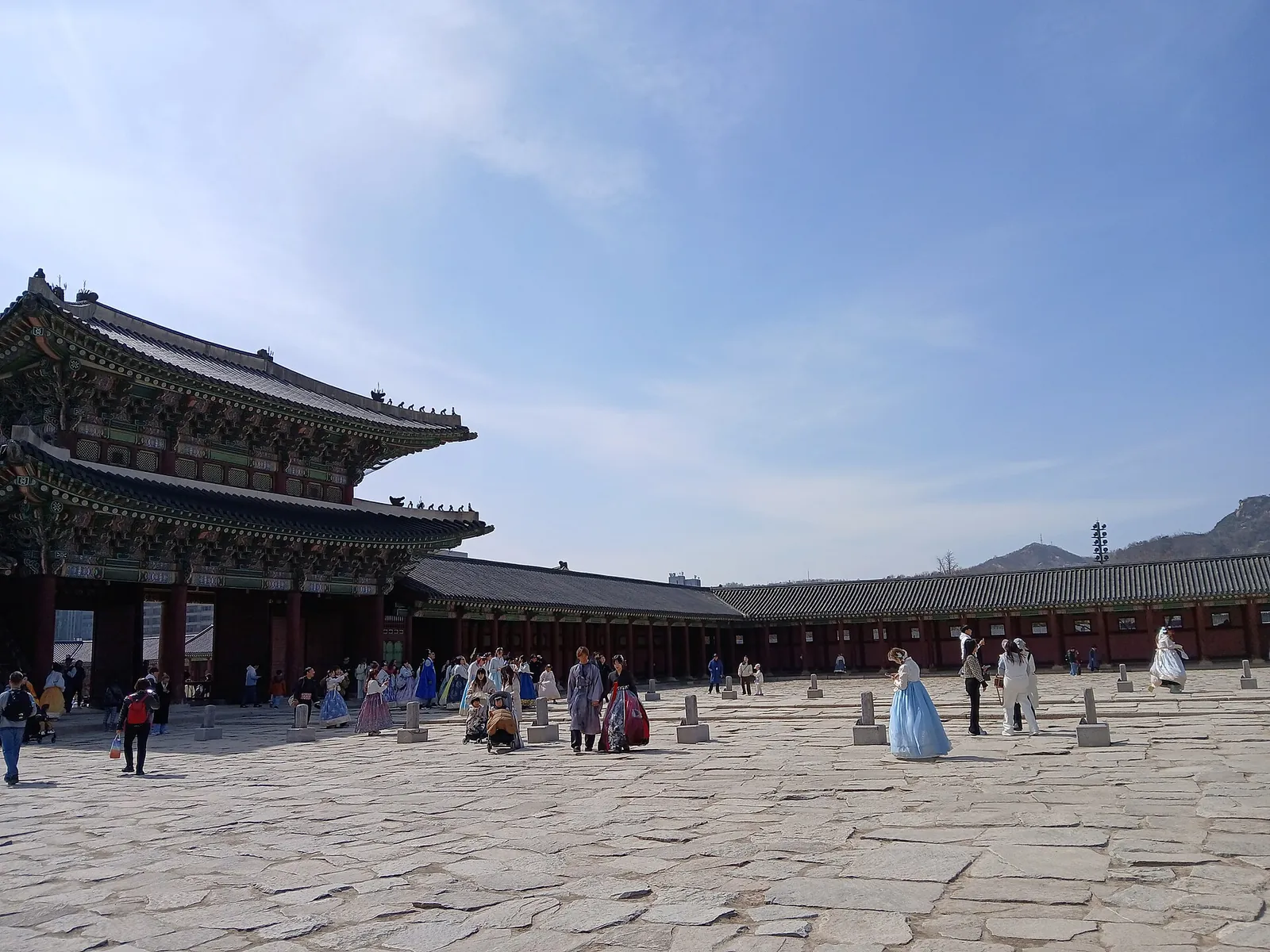 Visitors in hanbok in the main courtyard of Gyeongbokgung palace under a blue sky