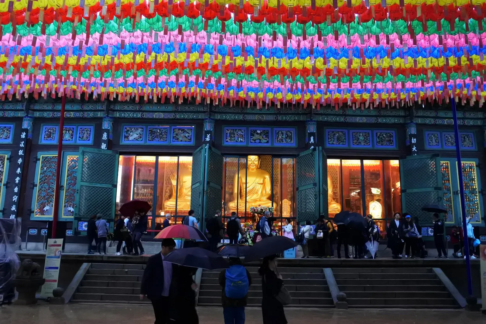 Rows of colourful paper lanterns above the main hall of Jogyesa in Seoul, with visitors on the steps