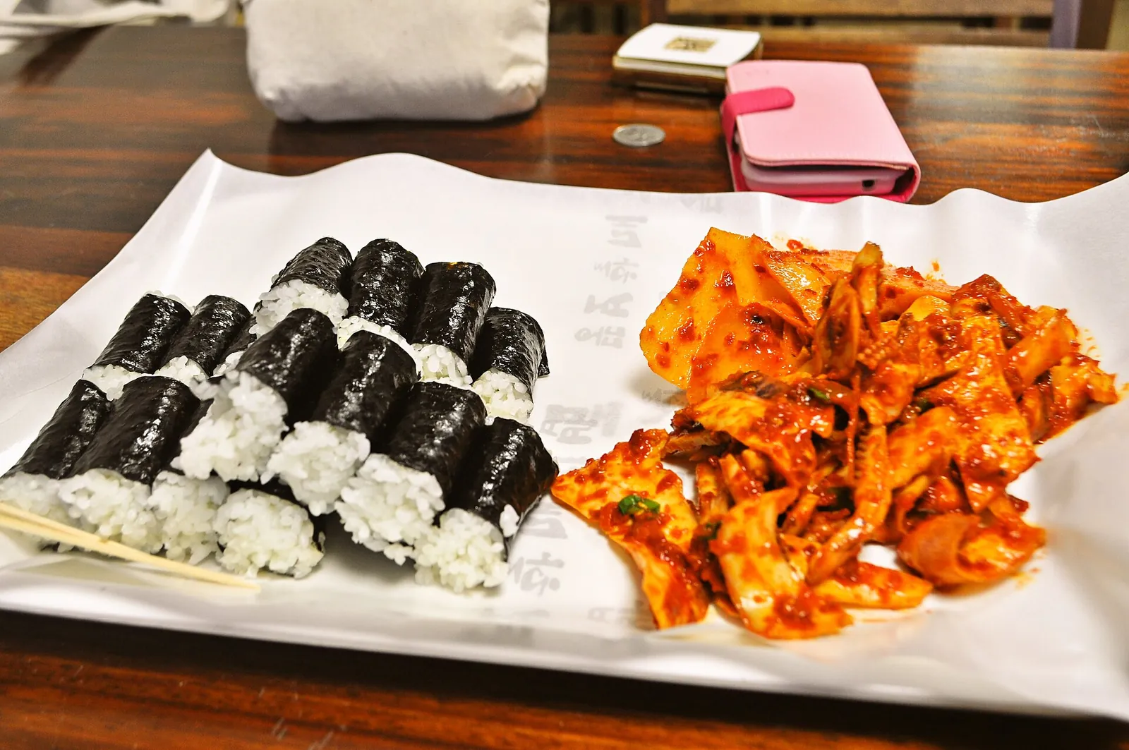 Plate of Chungmu gimbap, plain rice rolls in laver, with spicy squid and radish side dishes